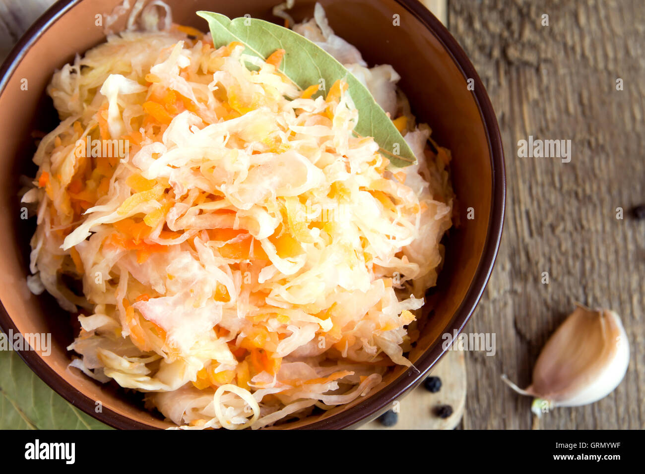 Sauerkraut in ceramic bowl on rustic wooden table with spices, traditional rustic winter food Stock Photo