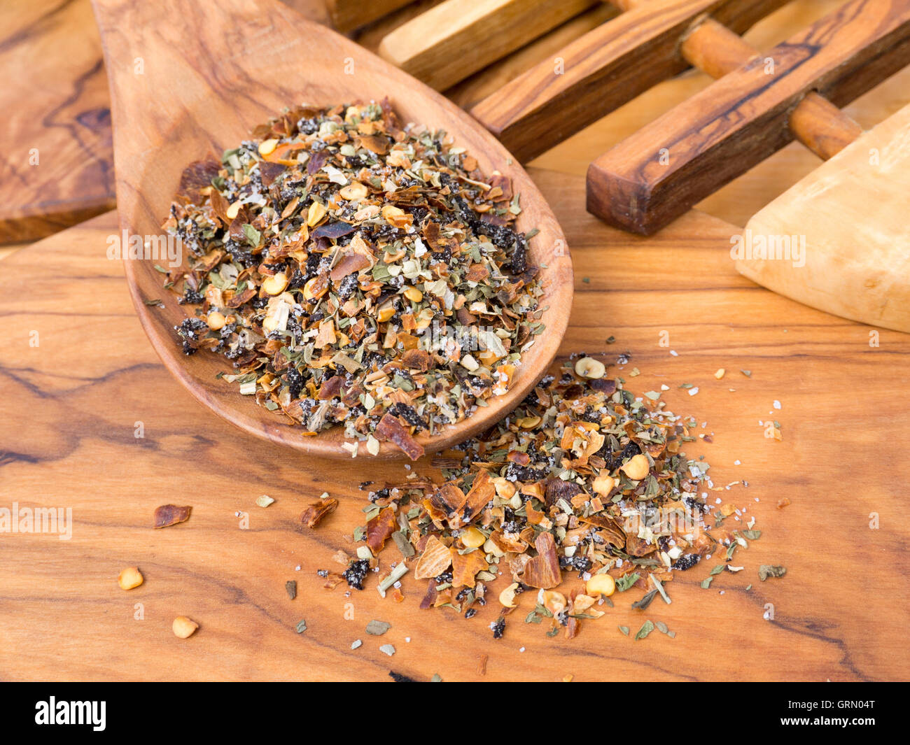Herbal seasoning in the wooden spoon on the olive wood cutting board Stock Photo