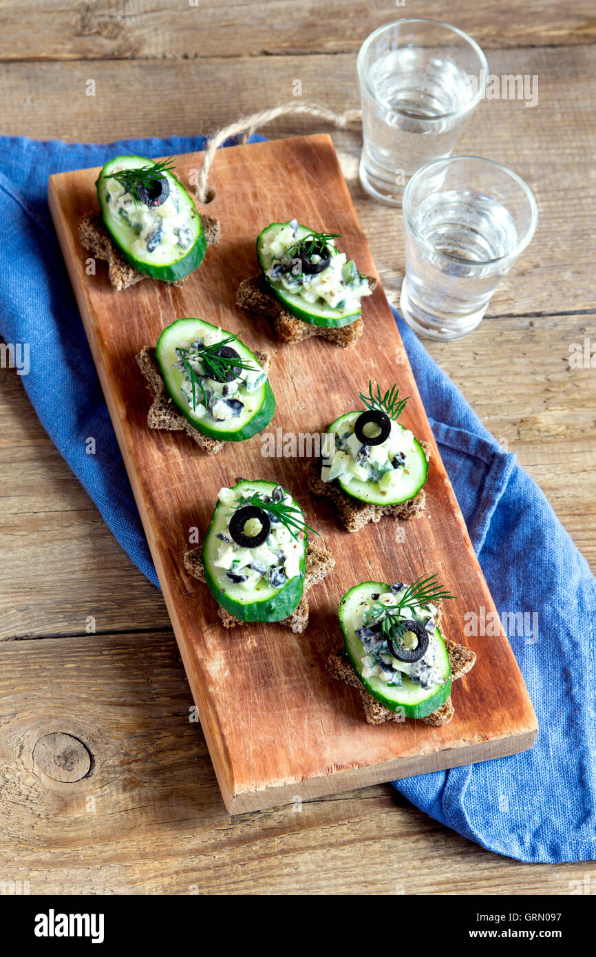 Mini sandwiches (snacks) with cucumber, olives and fish salad over ...