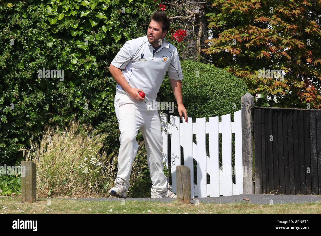 The ball is retrieved from a nearby garden - Herongate CC vs Havering-atte-Bower CC - Mid-Essex Cricket League - 21/06/14 Stock Photo