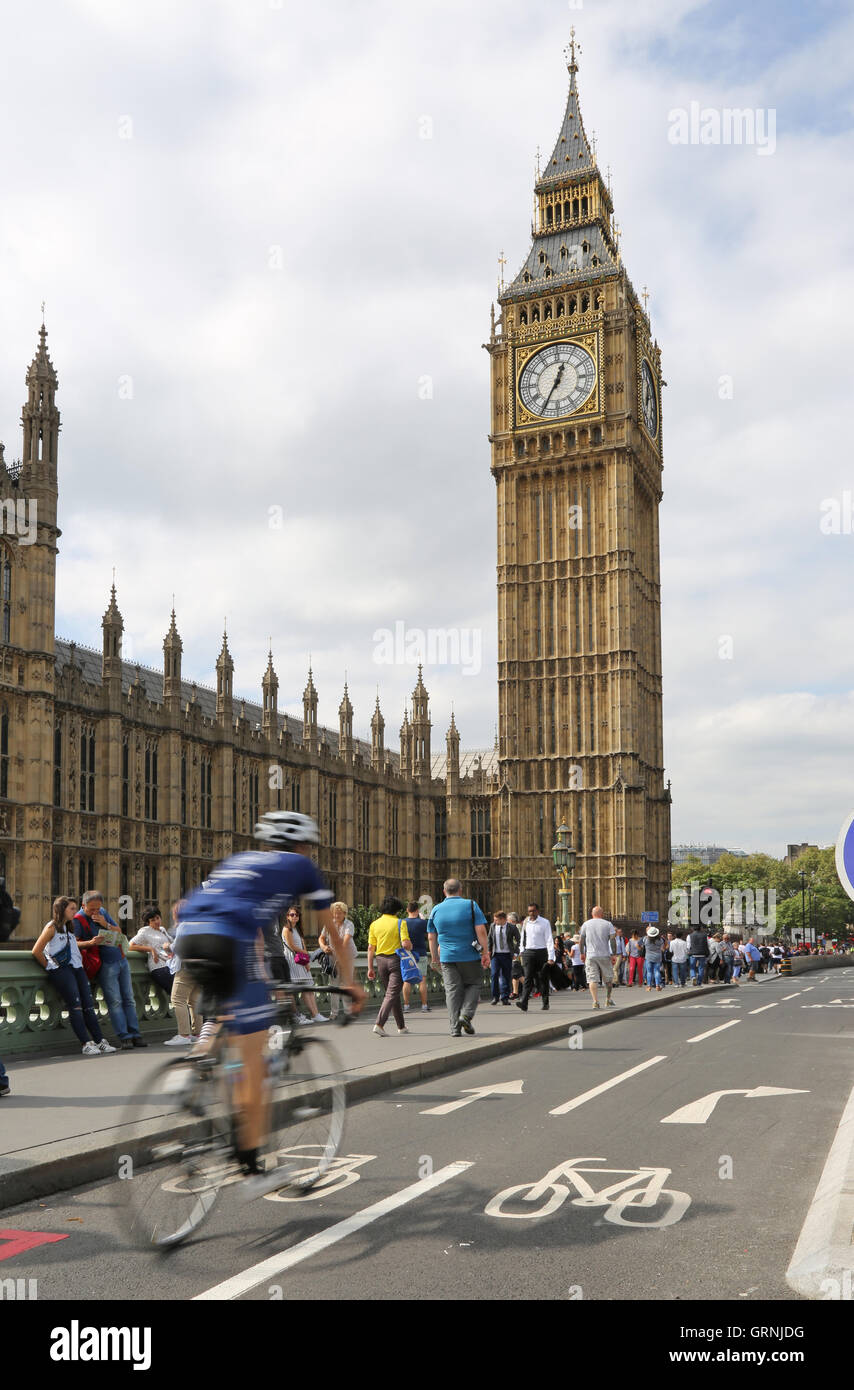 A cyclist (blurred through speed) on London's new cycle path on Westminster Bridge passes Big Ben and the Houses of Parliament. Stock Photo