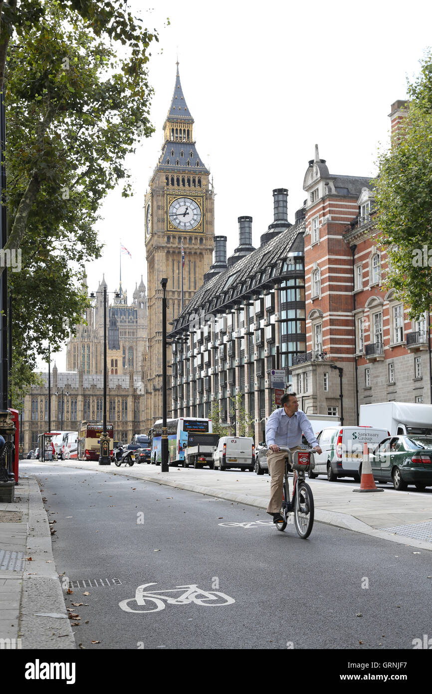 A cyclist on a hired 'Boris' bike uses London's new cycle path on Victoria Embankment. Shows Big Ben in the background. Stock Photo