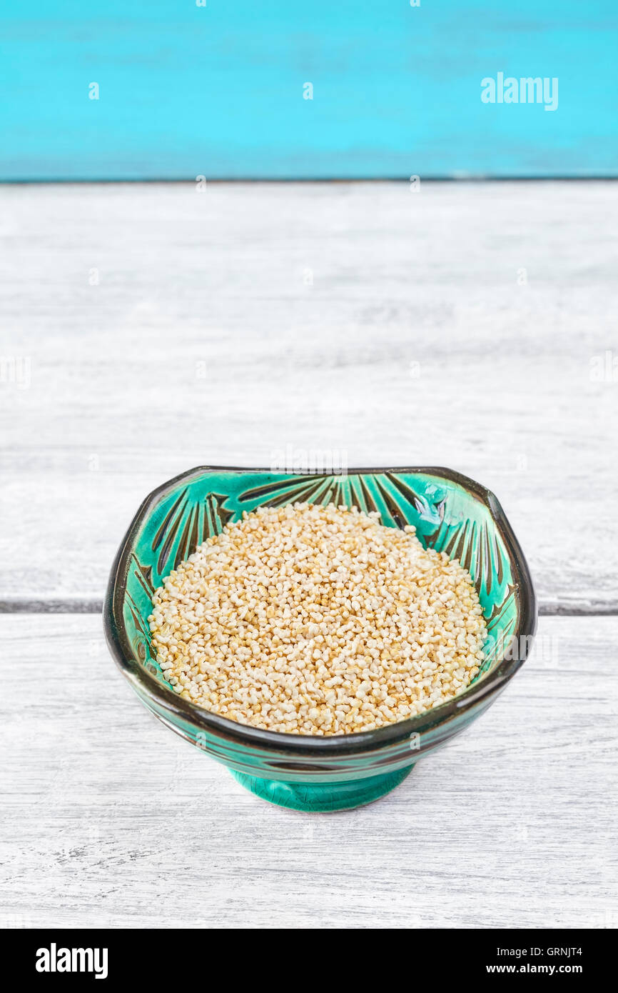 Amaranth seeds in a green bowl on rustic table, space for text. Stock Photo