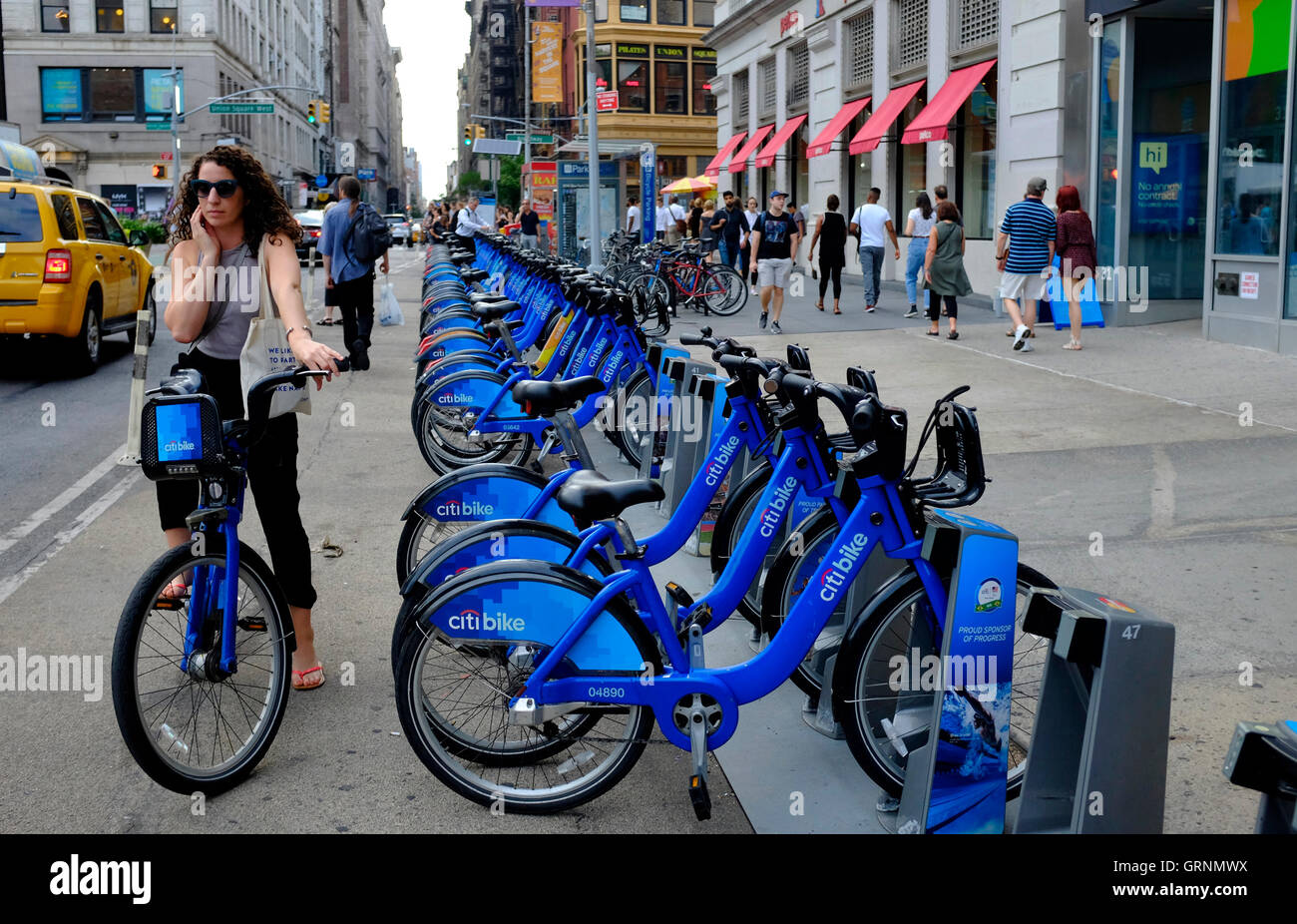 A female rider riding on a Citibike by a Citibike share station in Union Square.Manhattan.New York City,USA Stock Photo