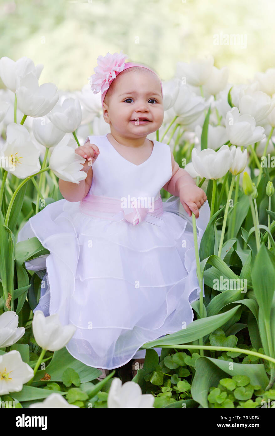 Little girl in an elegant dress to stand near blossoming tulips Stock ...