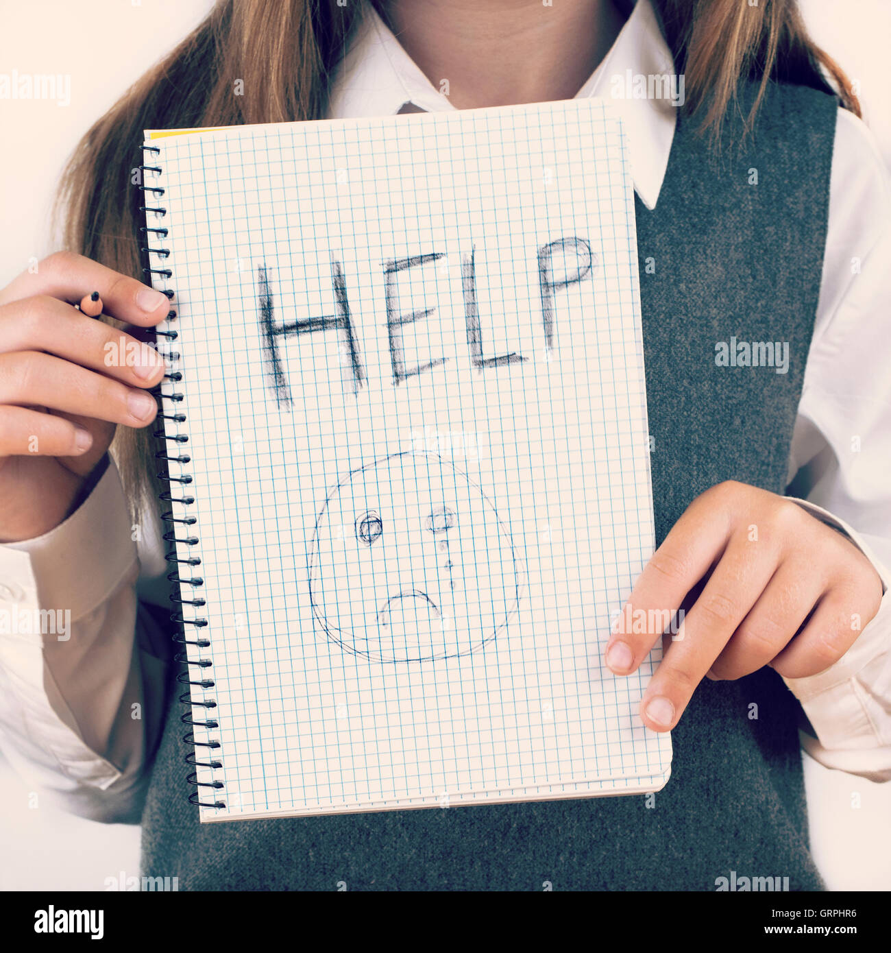 An image covering the Social Issues of child abuse, schoolchild in uniform asking for help by a written message saying Help with Stock Photo