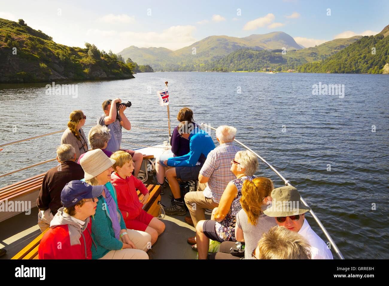 Tourists enjoying a cruise aboard the bow of Ullswater Steamers. Ullswater, Penrith, The Lake District National Park, Cumbria. Stock Photo