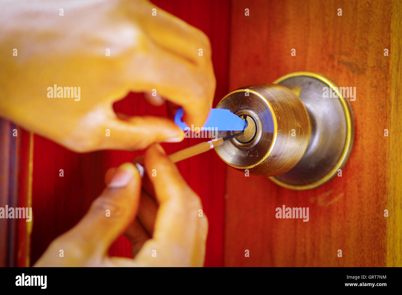 Closeup hands of locksmith using metal pick tools to open locked door