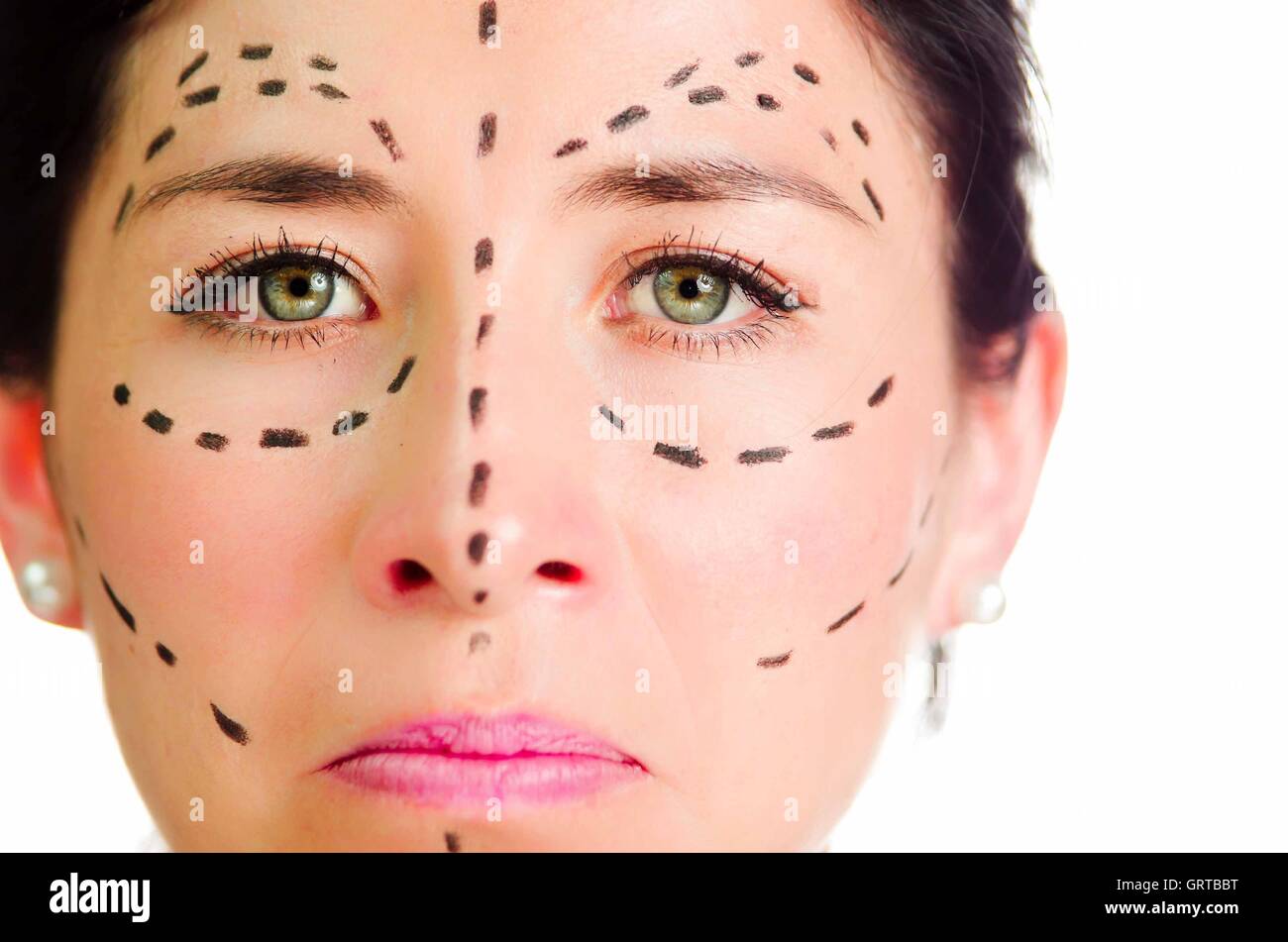 Closeup headshot caucasian woman with dotted lines drawn around face looking into camera, skeptical facial expression, preparing cosmetic surgery Stock Photo