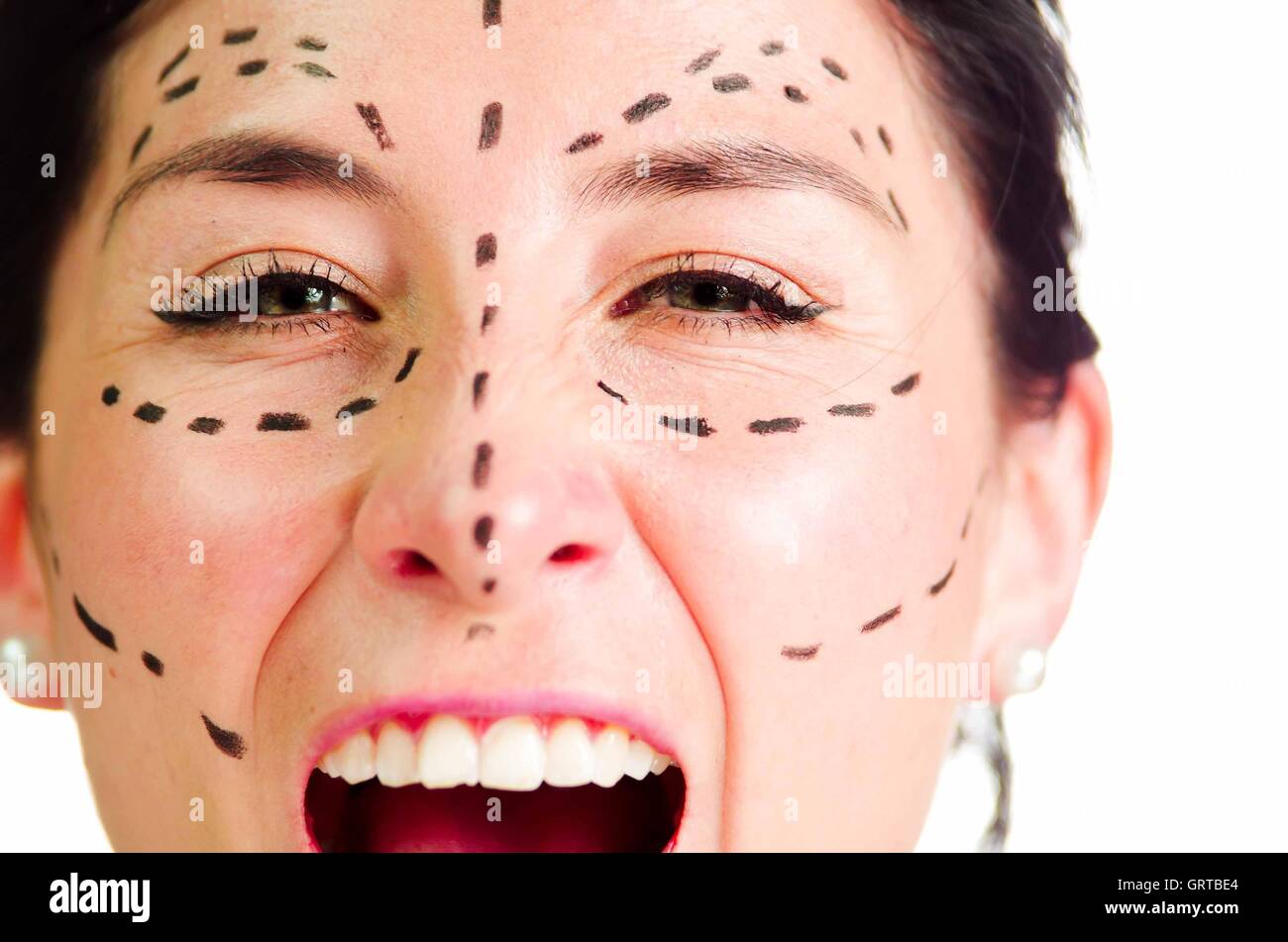 Closeup headshot caucasian woman with dotted lines drawn around face looking into camera, preparing cosmetic surgery, screaming facial expression Stock Photo