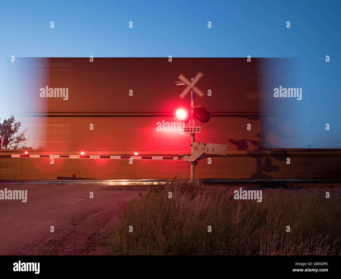 Freight by rail Canadian Pacific Railway speeding through a level crossing, Maple Creek, Saskatchewan, Canada. Stock Photo