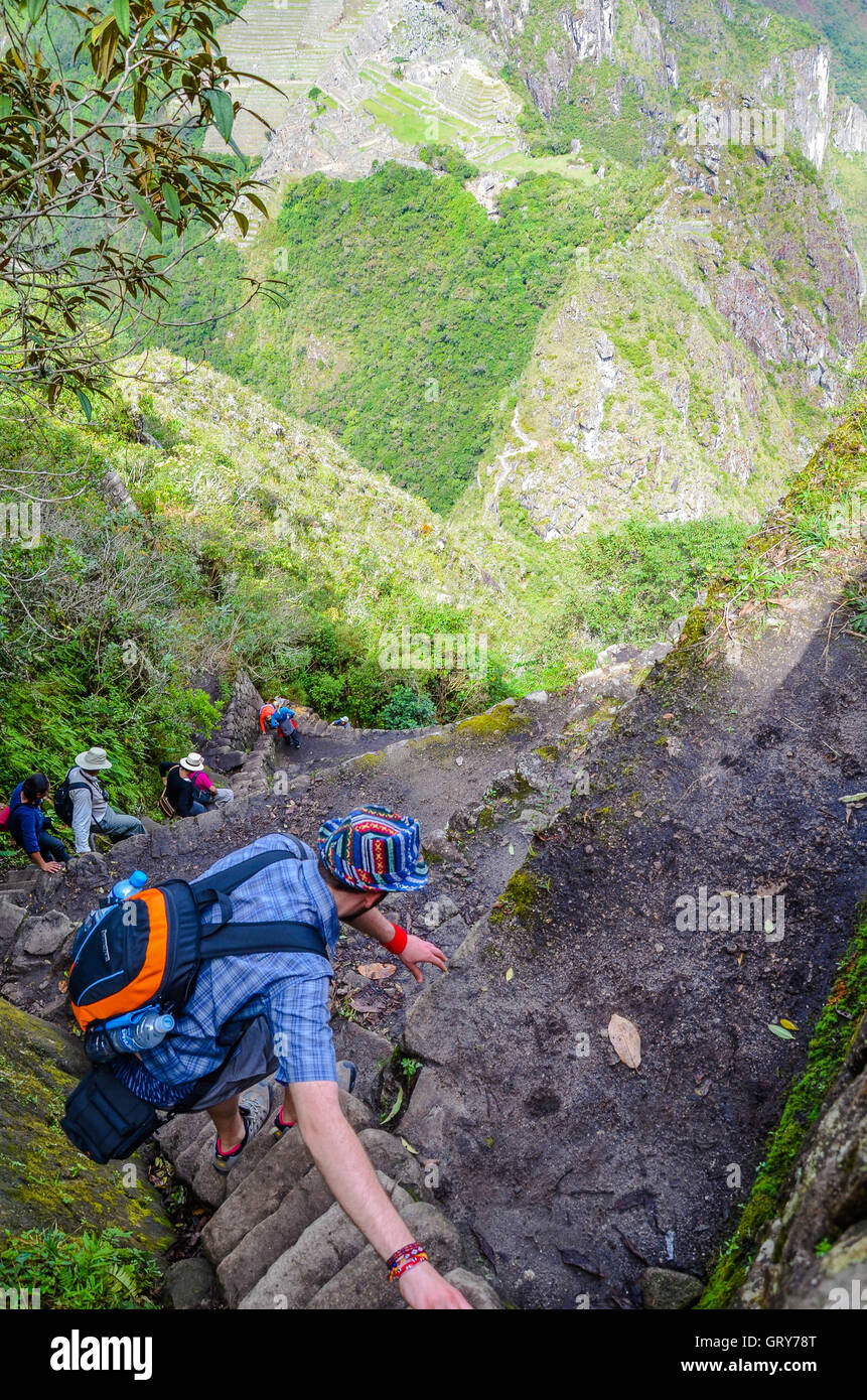 MACHU PICCHU, CUSCO REGION, PERU- JUNE 4, 2013: Tourist climbing Huayna Picchu mountain for one of the best panoramic views of M Stock Photo