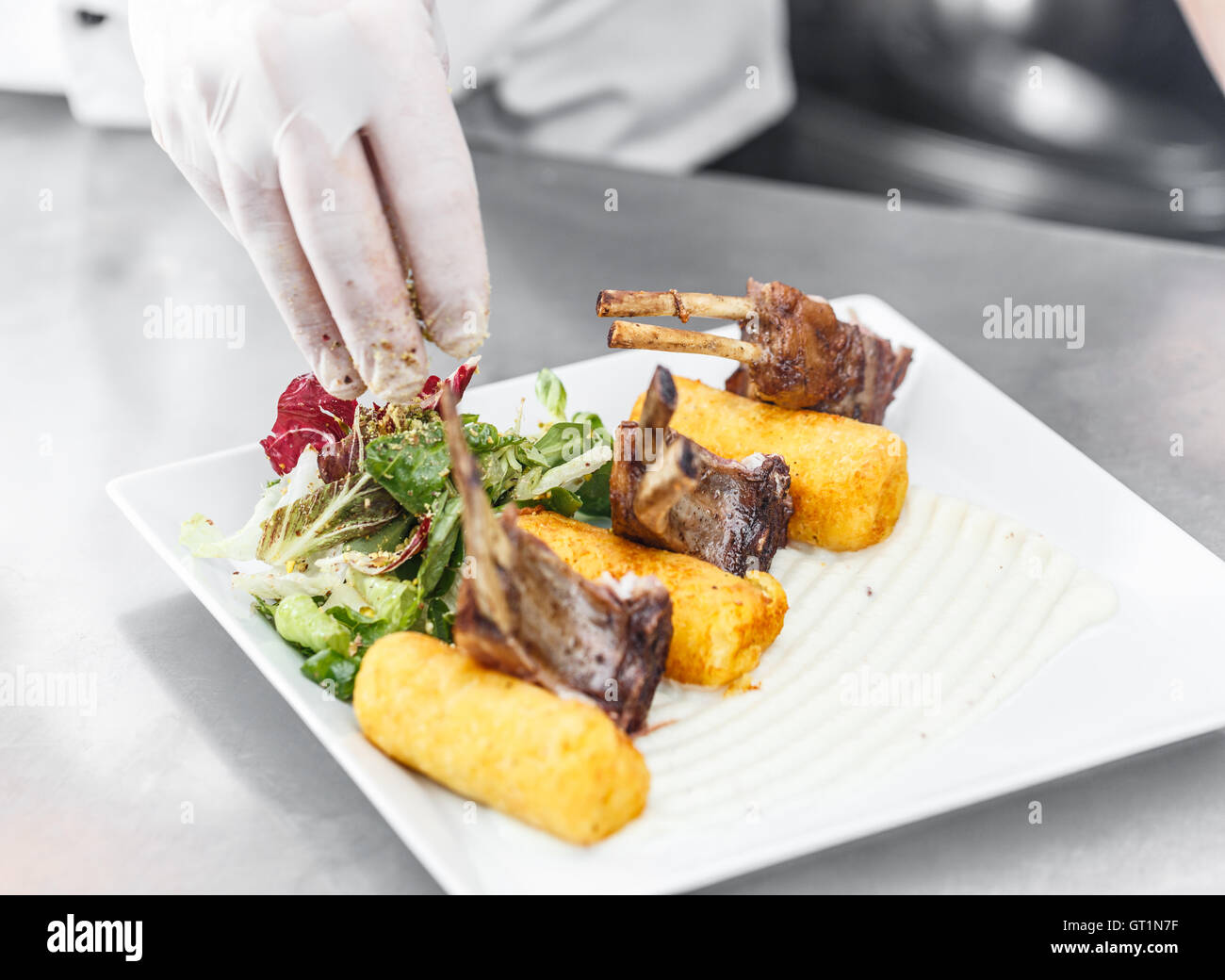 Chef arranged roasted lamb chops on white plate Stock Photo