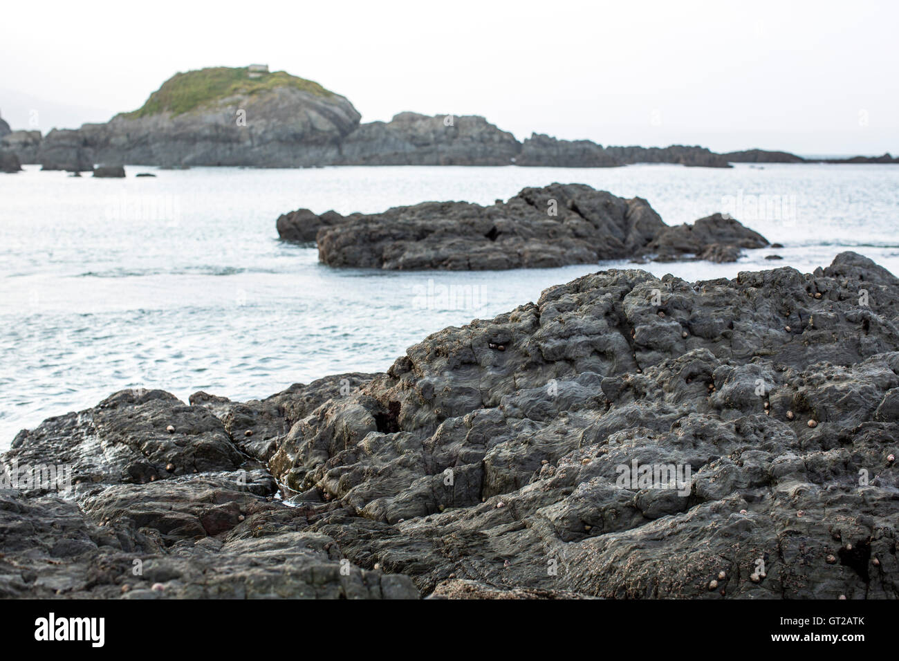 Grey stone rocks on a craggy part of the Uk coastline with grey sky and ...