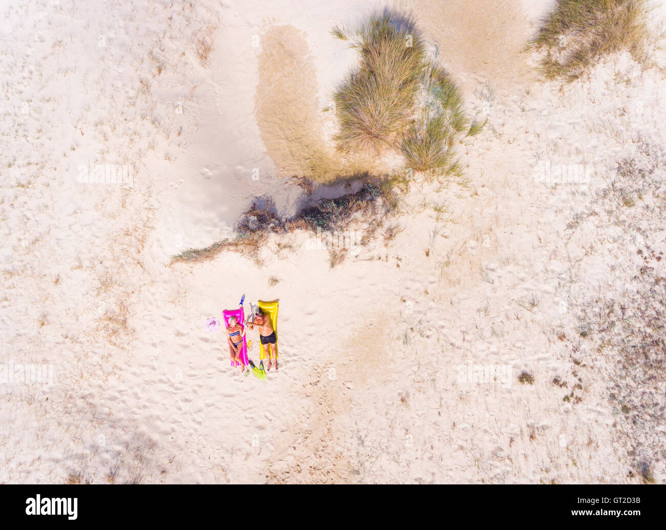 Aerial view of a couple sunbathing at the beach. Stock Photo
