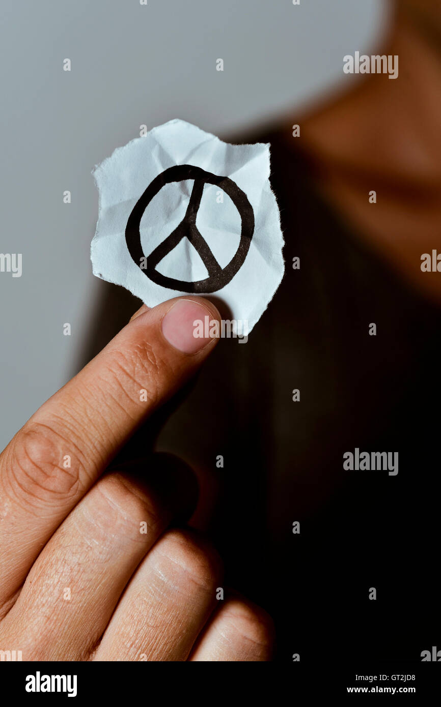 closeup of a young man showing a piece of paper with a peace symbol drawn in it Stock Photo