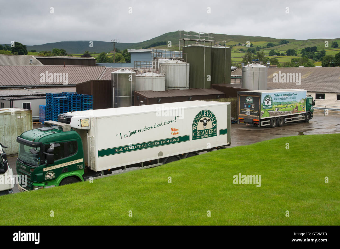 In the rain, 2 lorries with logos, parked outside the cheese factory - Wensleydale Creamery, Hawes, Yorkshire Dales, England. Stock Photo
