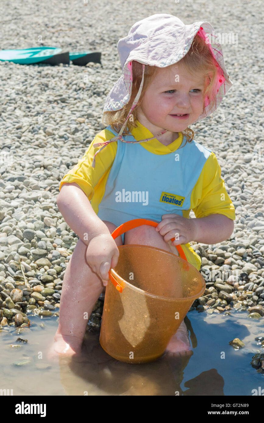Two 2 year old girl toddler child / kid with sun hat, swim suit bathing