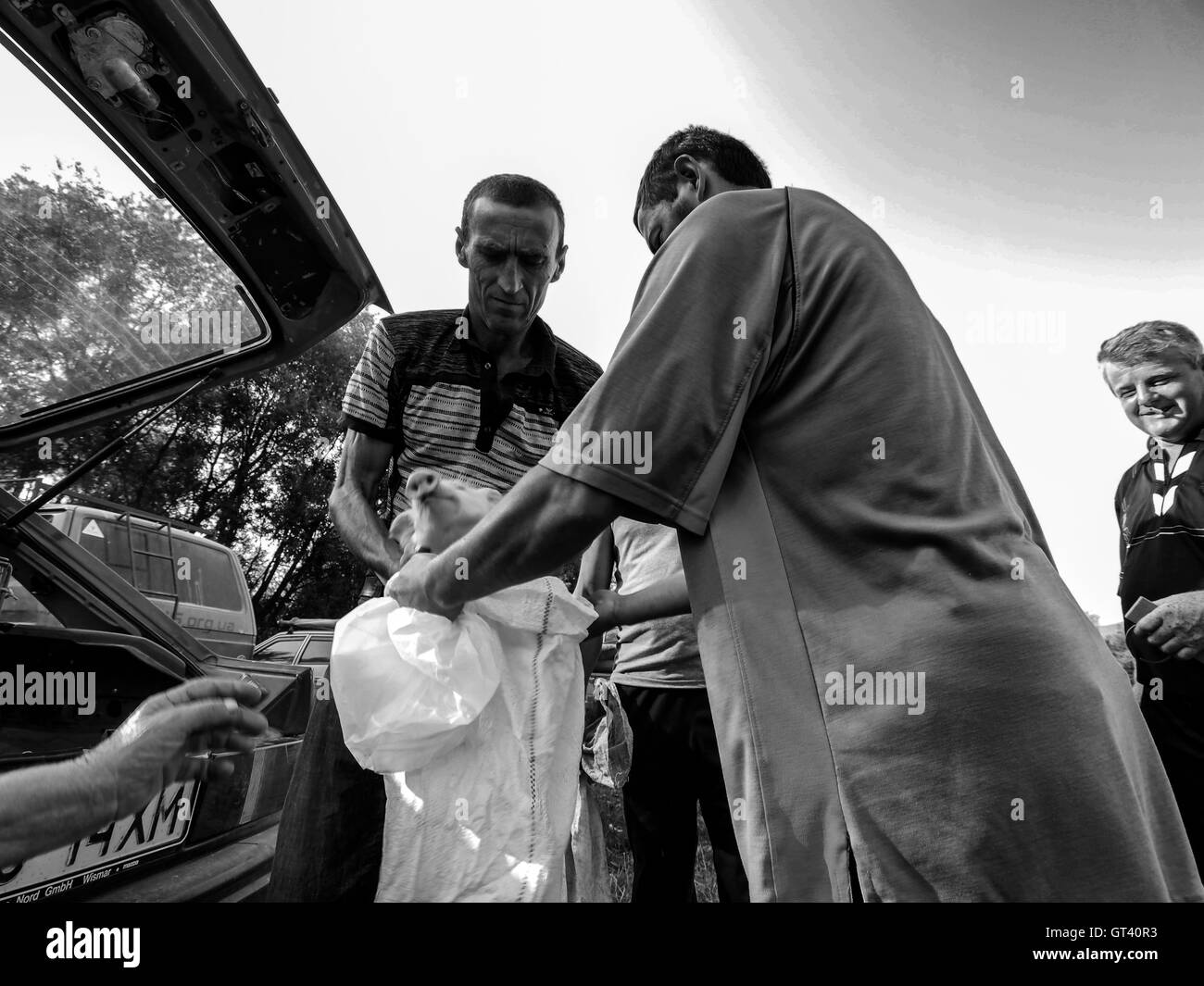 Seller puts into the bag that holds a man bought them pig on domestic animals market in the town of Kosov, Ivano-Frankivsk Oblas Stock Photo