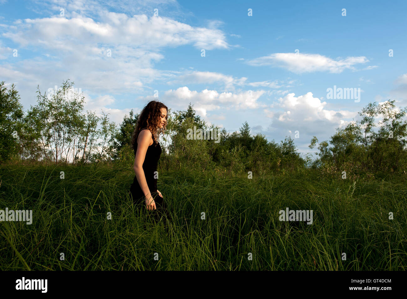 Beautiful girl walks in high grass Stock Photo - Alamy