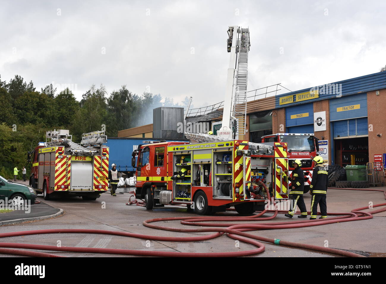 Devon, UK. 9th September, 2016. Tiverton Fire: The scene of a major fire at the premises of Warren Hughes Furniture Makers in Ormidale Square, Tiverton Business Park, Devon, at 16.00 BST on Friday 9th September 2016. The fire brigade were called at 11.23. Five hours later at least 6 fire appliances were still at the scene including two aerial platforms. Staff in the neighbouring units were also evacuated including the premises of North Devon Tyres and National Tyres & Autocare. Credit:  Tim Squires/Alamy Live News Stock Photo