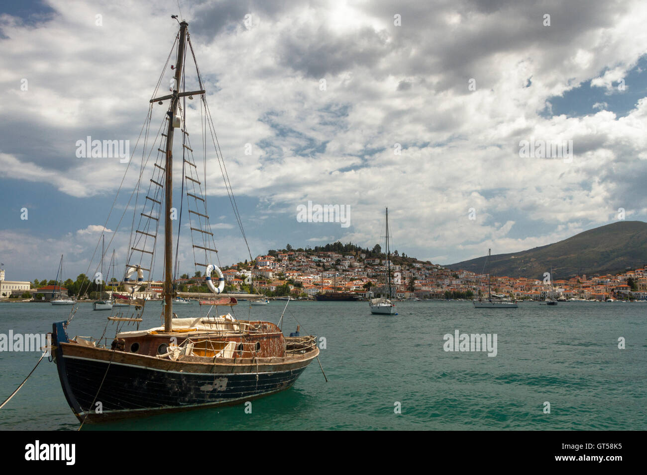 Old sailing boat and Poros island at the background, Greece. Poros is a