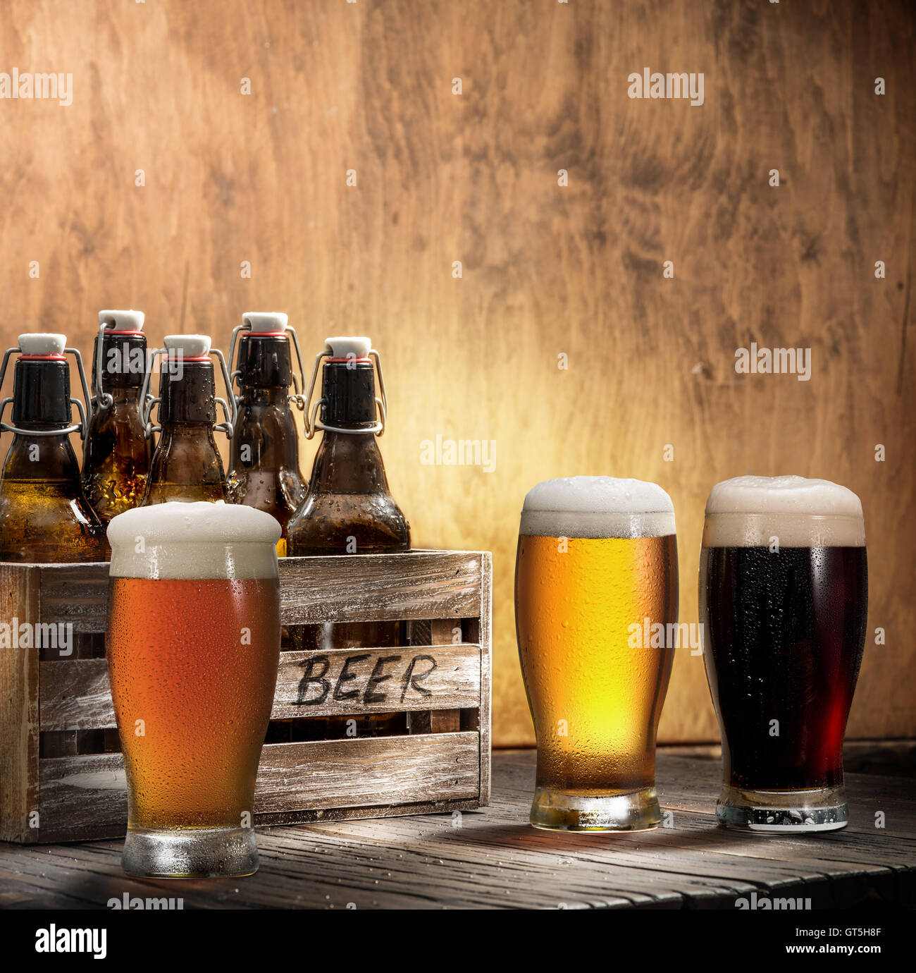 Crafting beer in bottles and glasses. On top of a wooden background. Stock Photo