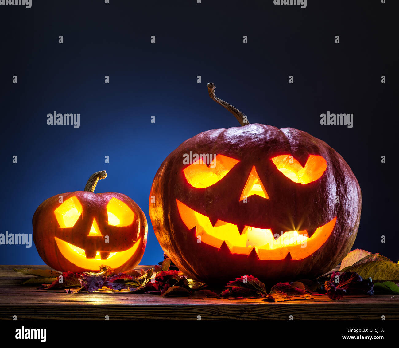 Grinning pumpkin lantern or jack-o'-lantern is one of the symbols of Halloween. Halloween attribute. Wooden background. Stock Photo