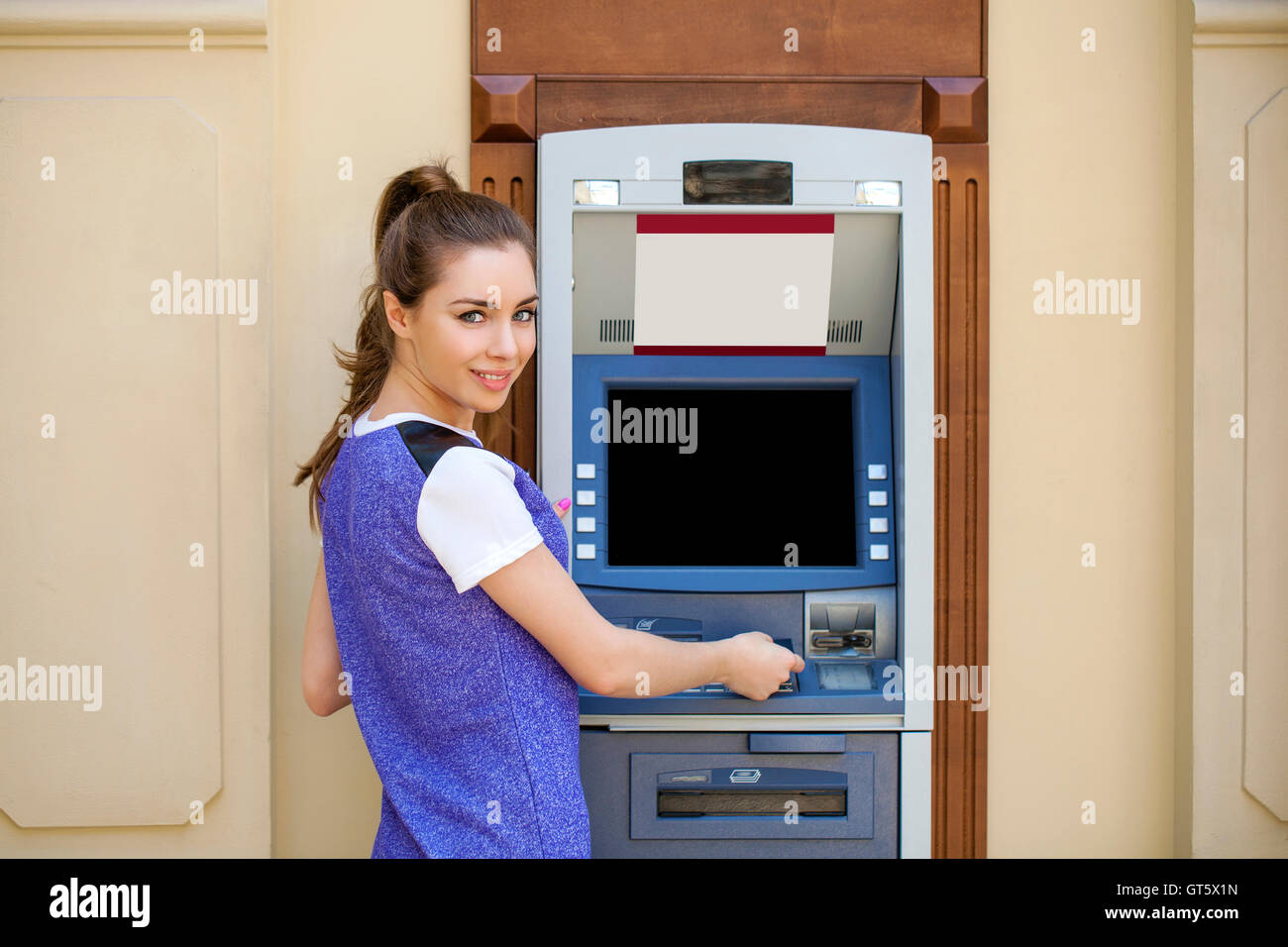 Brunette young lady using an automated teller machine. Woman withdrawing money or checking account balance Stock Photo