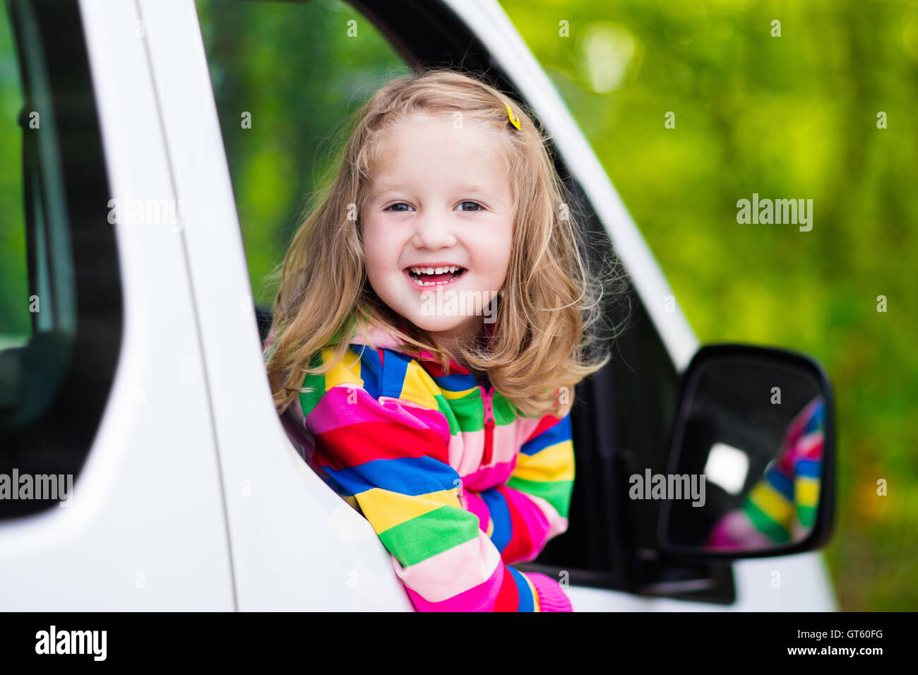 Little girl with funny pigtails watching out of car window sitting on