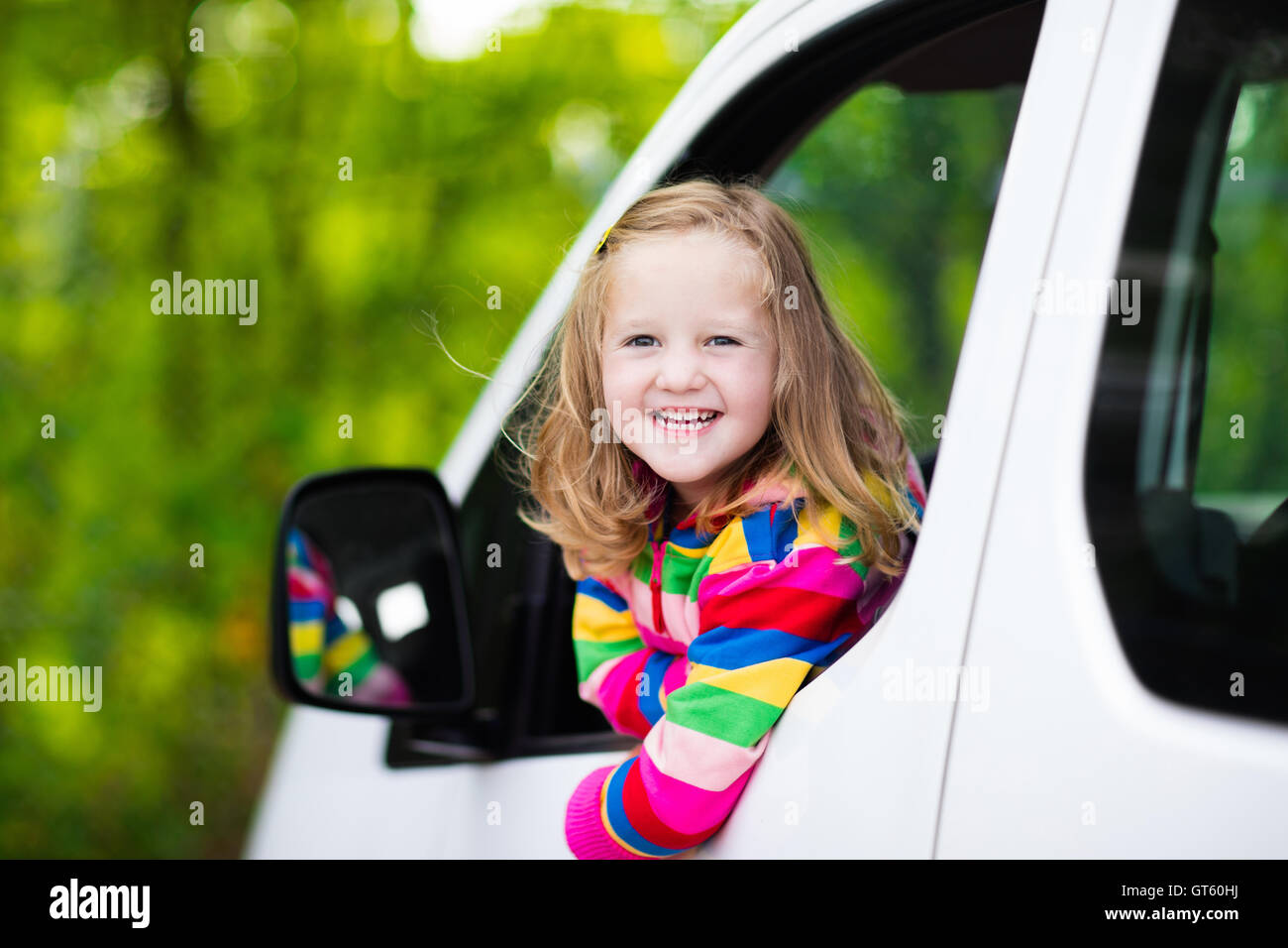 Little girl with funny pigtails watching out of car window sitting on