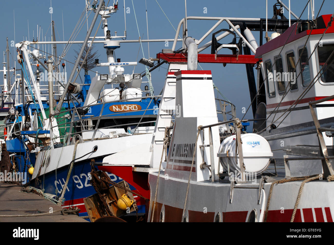 Fishing boats lined up against the harbour wall, Barfleur, Normandy, France. Stock Photo