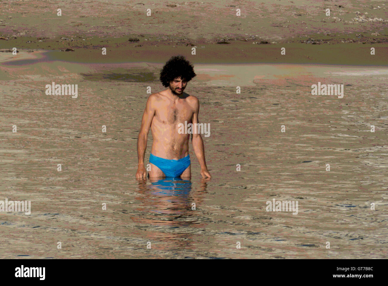 A young man big hair enters water Cefalu,Sicily Stock Photo
