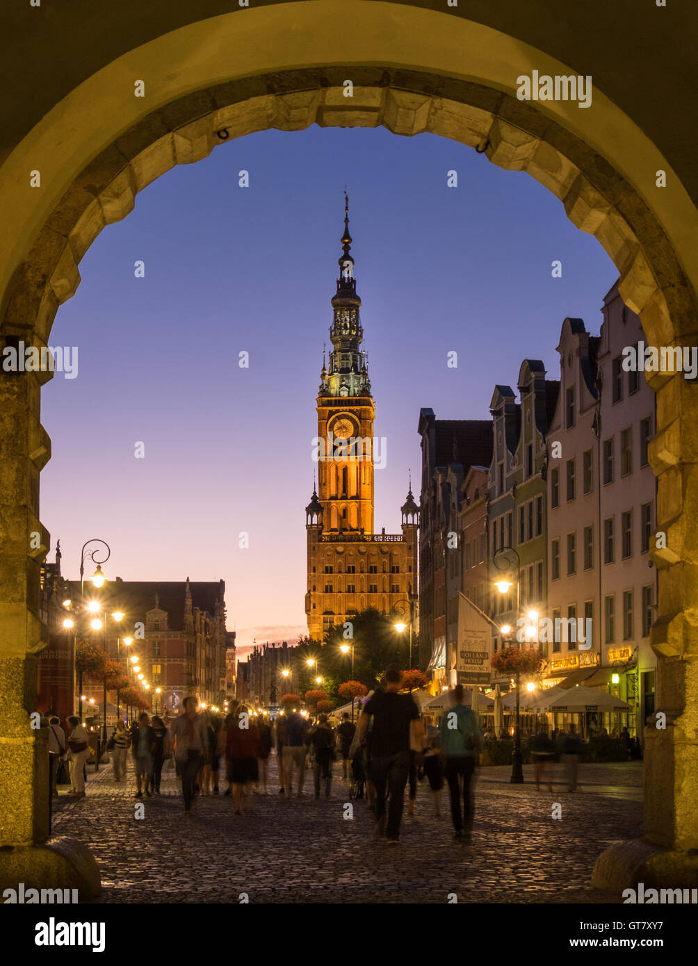 People walking through the arch of the Green Gate on Długa Street in Gdansk's Old Town, with Muzeum Historyczne Miasta Gdańska and Neptune's Fountain Stock Photo
