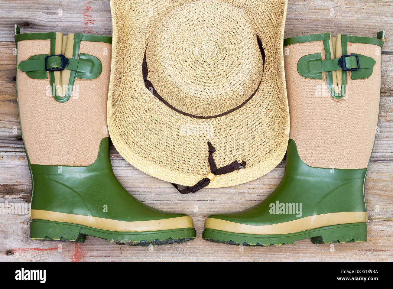 Garden fashion accessories with stylish rubber gumboots and wide brimmed straw hat in a symmetrical arrangement, view from above Stock Photo