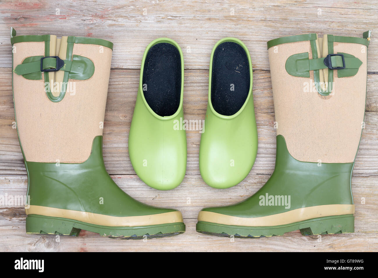 Stylish footwear for the garden with green rubber clogs and elegant matching green and beige gumboots in a symmetrical arrangeme Stock Photo