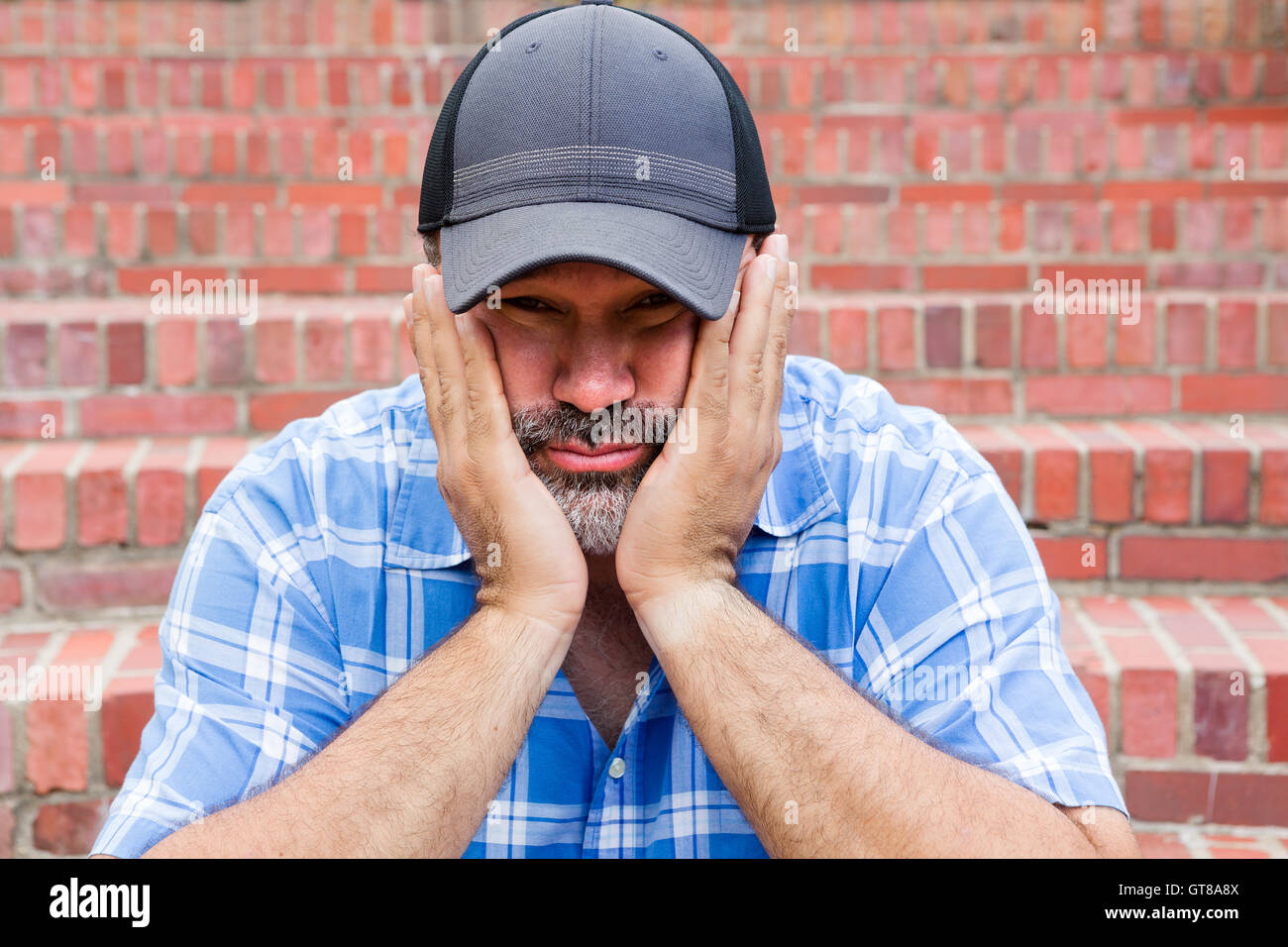 Boredom - the enemy of human happiness in a conceptual image of a middle-aged man with a goatee sitting resting his chin in his Stock Photo