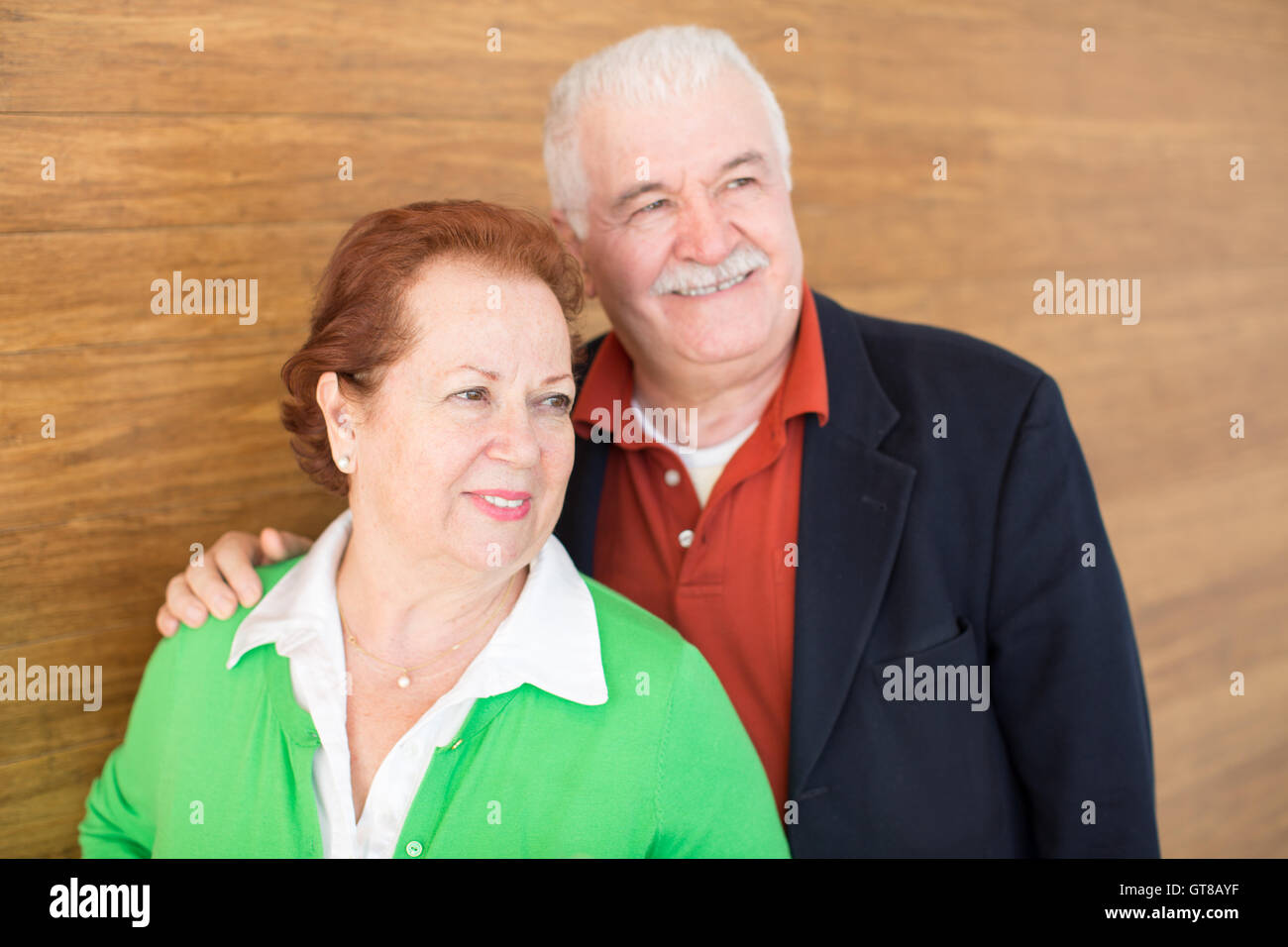 Close up Sweet Happy Retired Couple Posing in Front of a Wooden Wall Background. Stock Photo