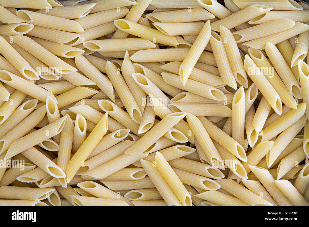 Background texture of penne, rigate or ziti pasta with its hollow diagonally cut tubes used in