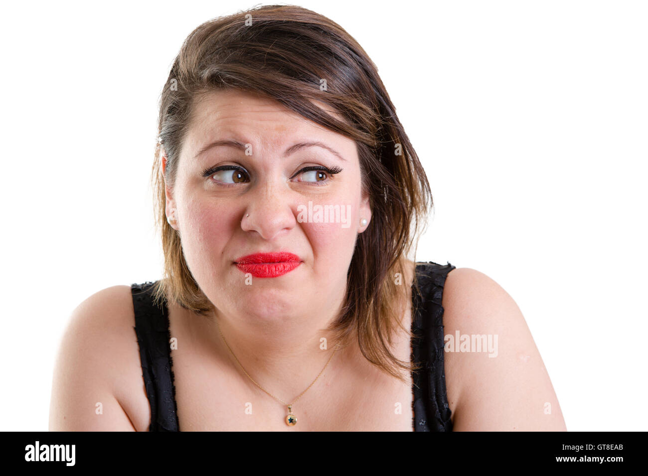 Expressive woman showing her revulsion and aversion glancing to the side with a frown and grimace as she hunches her shoulders, Stock Photo
