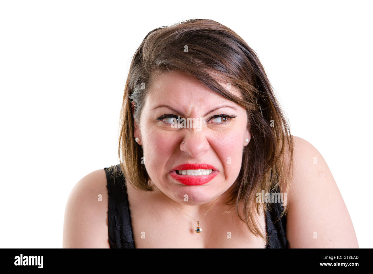 Angry jealous vindictive woman hunching her shoulders and snarling as she looks furtively sideways with a baleful expression, on Stock Photo