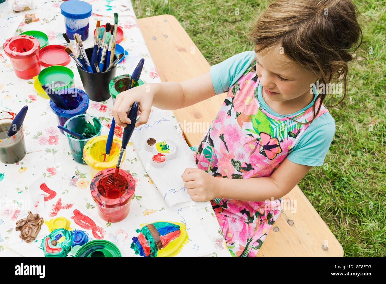 5 year old girl painting at a table in the garden, Sweden Stock Photo