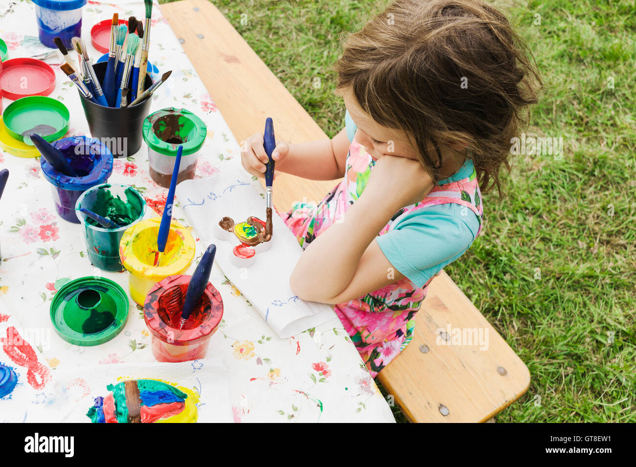 5 year old girl painting at a table in the garden, Sweden Stock Photo