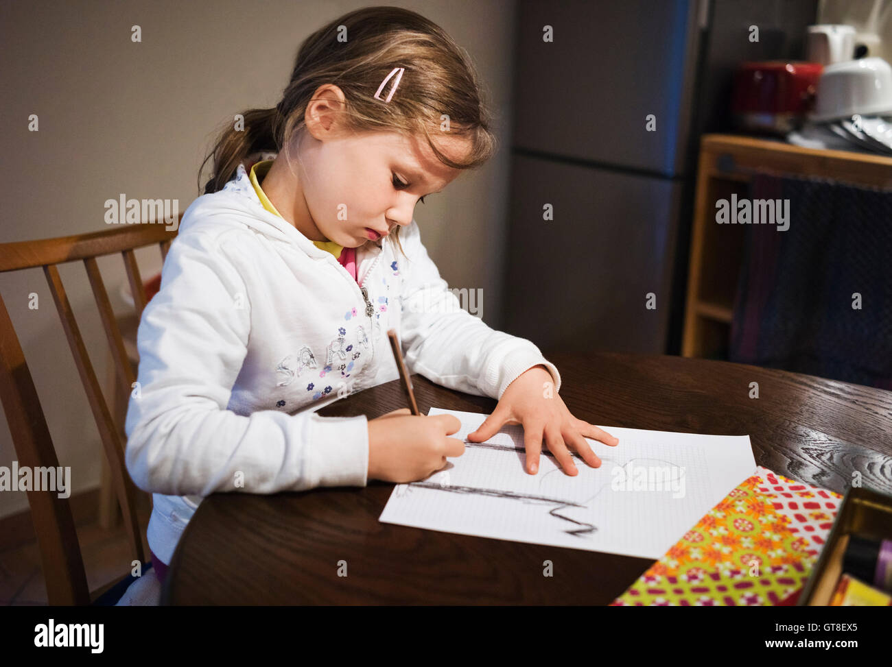 5 year old girl sitting at the table and drawing with a pencil, Germany Stock Photo