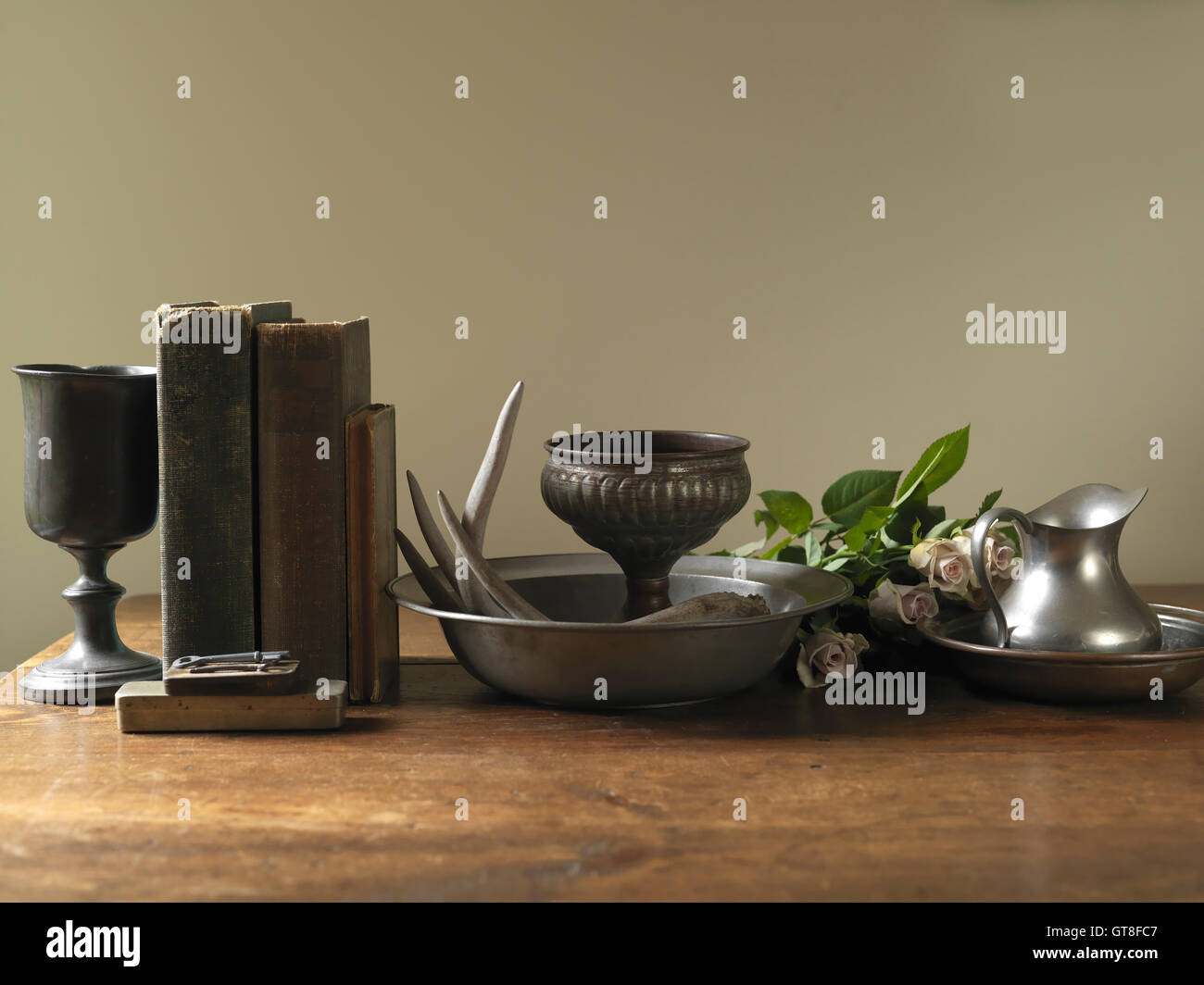 Still Life of Old Books with Silver Goblets, Bowls, Jug and Roses Stock Photo