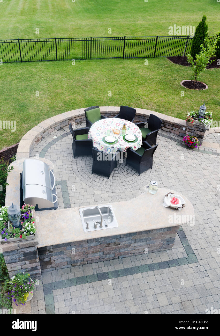 View looking down at a brick paved outdoor living area on an openair patio with a gas BBQ and