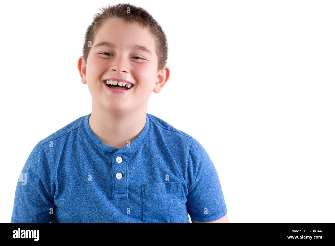 Carefree attractive young boy enjoying a good joke standing laughing at the camera, head and