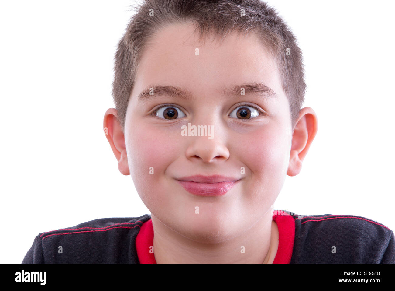 Head and Shoulders Close Up Portrait of Young Boy Wearing Black and Red Shirt Looking at Camera with Wide Eyes and Closed Mouth Stock Photo