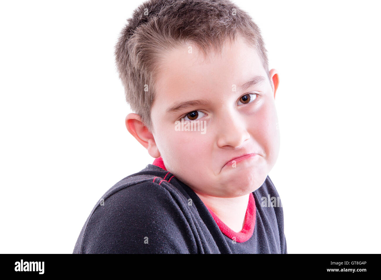 Head and Shoulders Close Up Portrait of Young Boy with Brown Eyes Looking at Camera with Down Turned Mouth in Studio with White Stock Photo