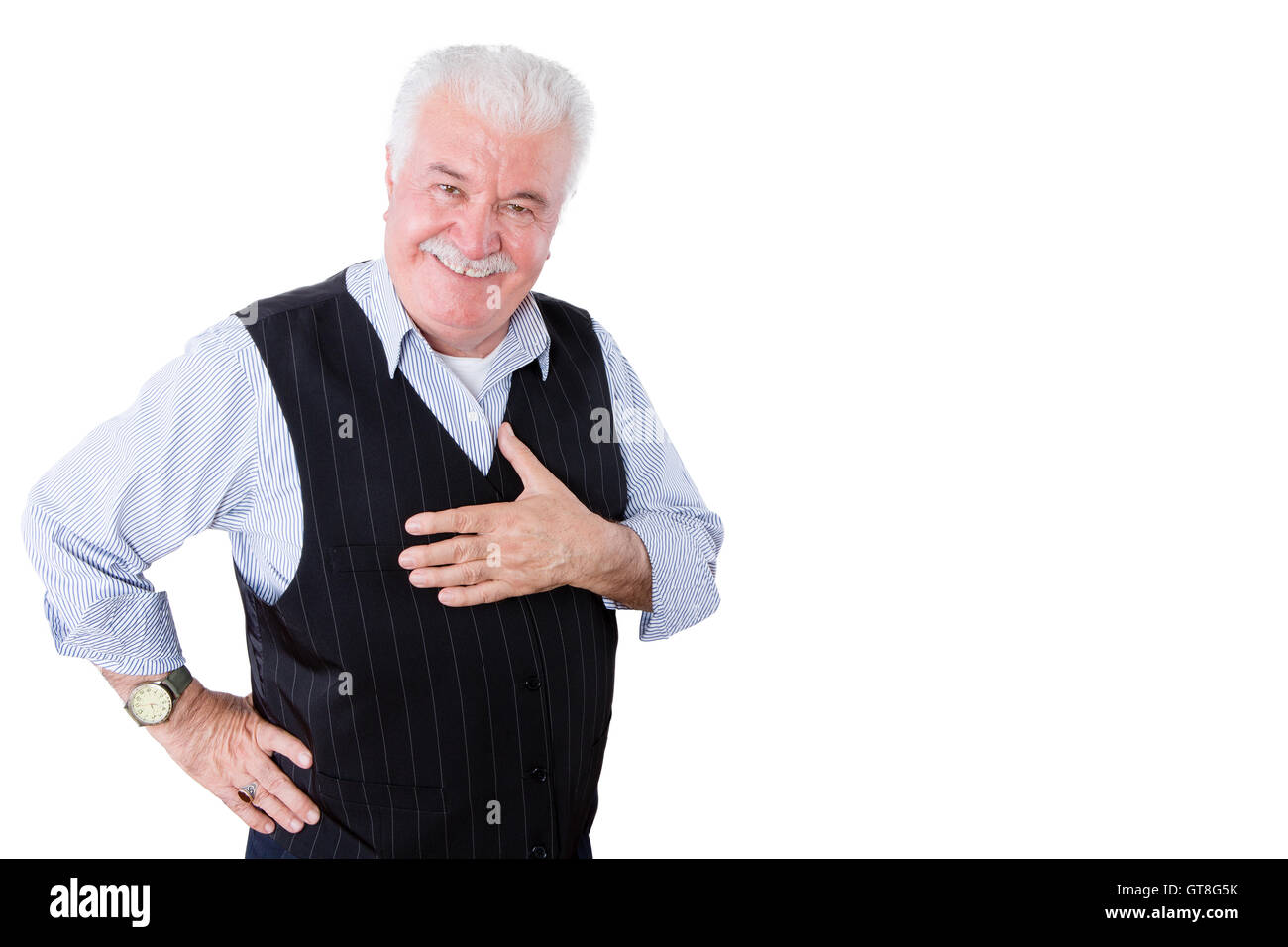 Gracious polite elderly man showing his gratitude and thanks holding his hand to his heart and looking at the camera with a beam Stock Photo